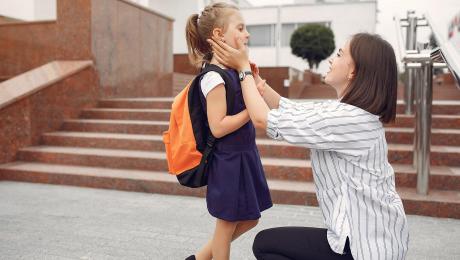 mother kneeling down adjusting kids clothes